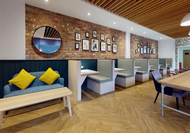 Sofa with yellow pillows bench booths and tables Common area at iQ Studios 51 in Birmingham Student Accommodation