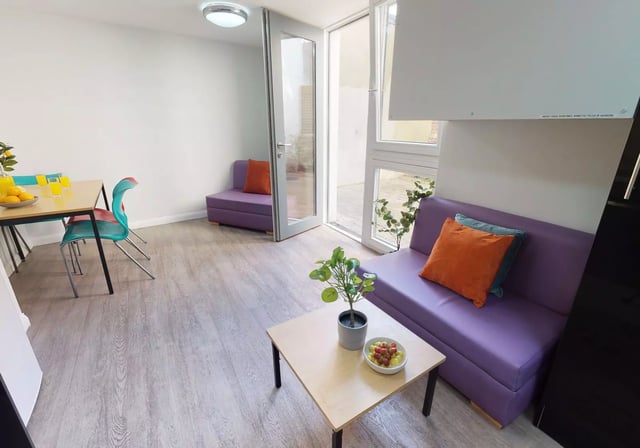 Purple sofas coffee table and dining set living room at iQ Sawmills in Brighton Student Accommodation