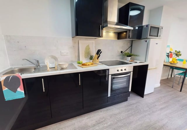 Sink oven microwave fridge and dining table kitchen at iQ Sawmills in Brighton Student Accommodation