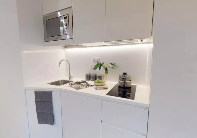 Modern white kitchen with microwave sink and stovetop kitchen at iQ Brighton in Brighton Student Accommodation