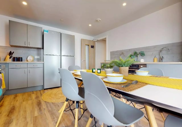 Dining table with chairs and kitchen area exterior at iQ Weaver Place in Coventry Student Accommodation