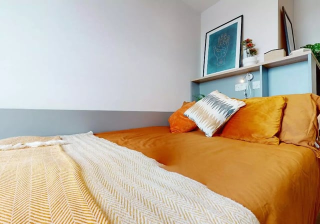 Bed with orange duvet and patterned throw Bedroom at iQ Weaver Place in Coventry Student Accommodation