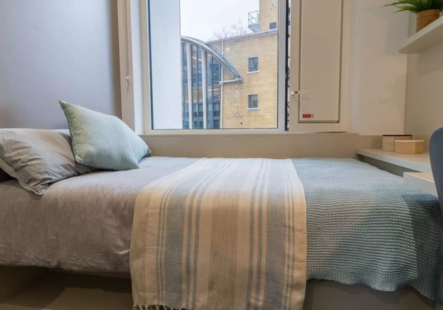 Bed with pillows and throw overlooking courtyard bedroom at iQ Vega London in London Student Accommodation