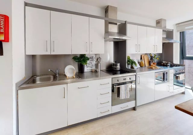 Modern kitchen with white cabinets sink oven and microwave kitchen at iQ Haywood House in London Student Accommodation
