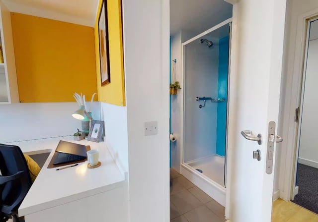 Desk with laptop shower cubicle bathroom at iQ Haywood House in London Student Accommodation
