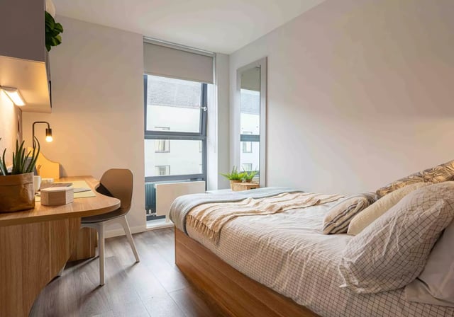 Bed desk chair and mirror bedroom interior at iQ Sterling Court in London Student Accommodation