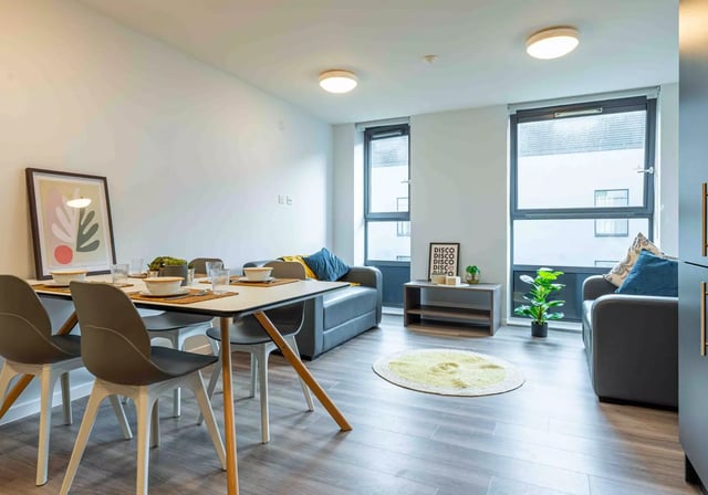 Dining table with chairs sofa rug living room at iQ Sterling Court in London Student Accommodation