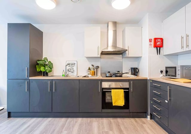 Modern kitchen with dark grey cabinets microwave oven and kettle kitchen at iQ Sterling Court in London Student Accommodation