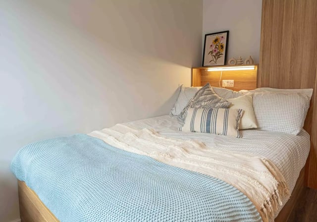 Bed with blue blanket and pillows bedroom at iQ Sterling Court in London Student Accommodation