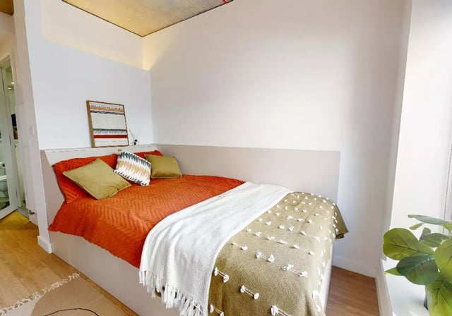 Bed with orange bedding pillows and throws Bedroom at iQ Flinders House in London Student Accommodation