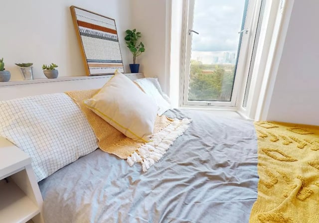 Bed with pillows and throws window view bedroom at iQ East Court in London Student Accommodation