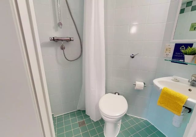 Shower toilet sink and yellow towel bathroom at iQ Manchester Gardens in Manchester Student Accommodation