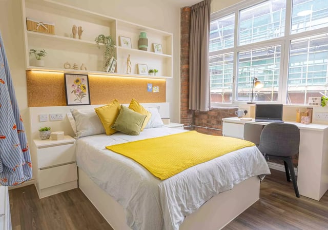 Bed with yellow blanket desk and laptop bedroom at iQ Hollingworth House in Manchester Student Accommodation