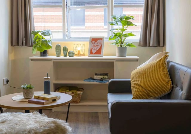 Sofa plants coffee table books living room at iQ Hollingworth House in Manchester Student Accommodation