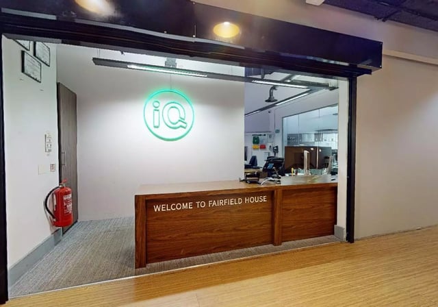 Reception desk with logo and fire extinguisher reception area at iQ Hollingworth House in Manchester Student Accommodation