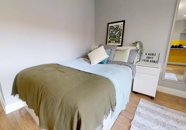 Bed with pillows throws framed art lit sign bedroom at iQ The Brickworks in York Student Accommodation