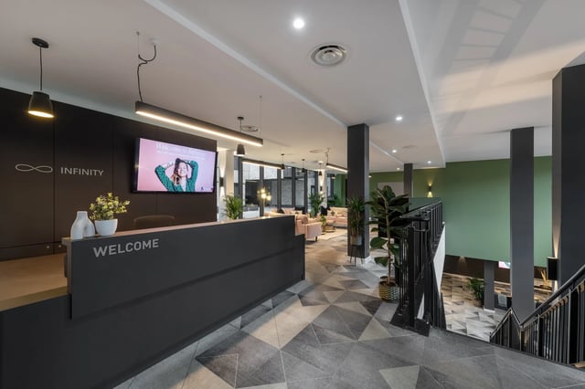 Reception desk with welcome screen and seating area. at Infinity Coventry in Coventry Student Accommodation