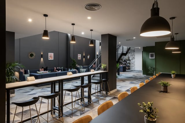 Long table with stools and lounge seating living room at Infinity Coventry in Coventry Student Accommodation