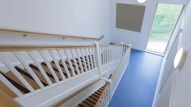 Wooden staircase with white railings and blue floor Staircase at Treliske Key Workers in Truro Student Accommodation