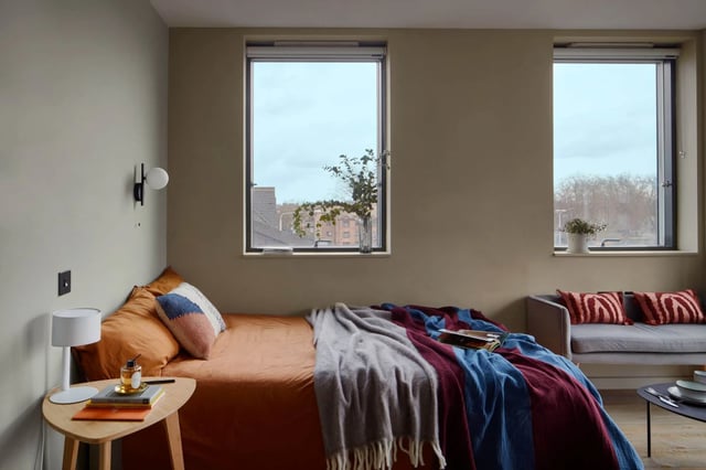 Bed side table with lamp couch and window bedroom at Tribu Kingston in Kingston Upon Thames Student Accommodation