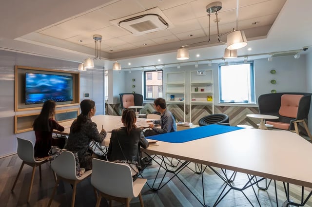 Students around table with TV living area at Kaplan Living West Village in Glasgow Student Accommodation