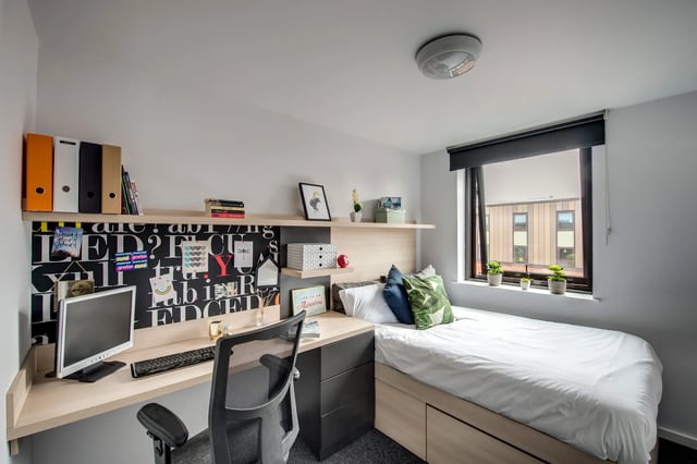 Desk bed shelves computer monitor and chair bedroom at Kaplan Living West Village in Glasgow Student Accommodation
