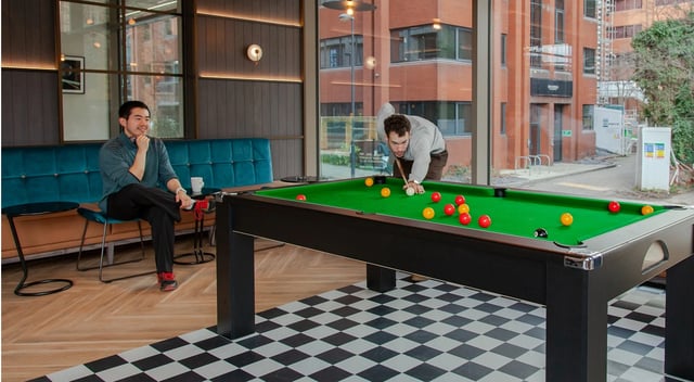 Billiard table with balls and players in lounge living room at Symons House in Leeds Student Accommodation