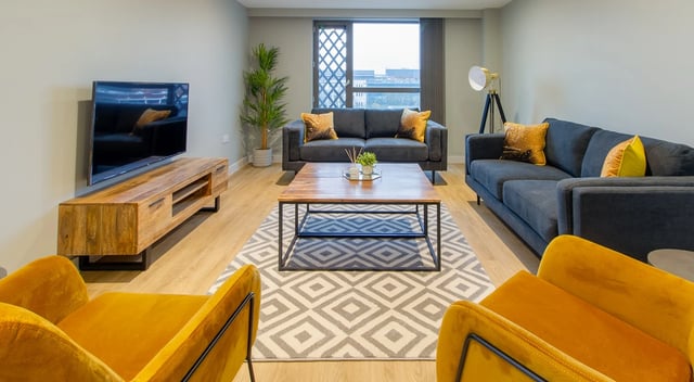 Two grey sofas yellow chairs coffee table living room at Symons House in Leeds Student Accommodation