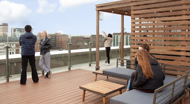 People relaxing on rooftop seating area with cityscape at Symons House in Leeds Student Accommodation