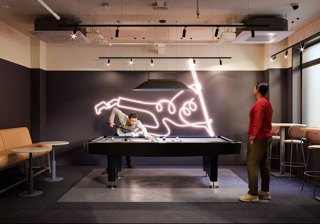 Billiard table with people playing and neon art playing area at Longwood Place in Coventry Student Accommodation