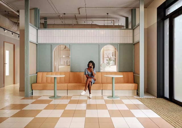 Woman sitting on orange banquette near tables lounge area at Longwood Place in Coventry Student Accommodation