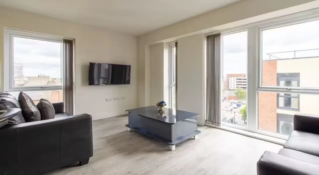 Black sofas large coffee table wall TV living room at Dover Street Apartments in Leicester Student Accommodation