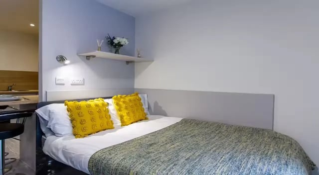 Bed with yellow pillows and grey throw bedroom at Dover Street Apartments in Leicester Student Accommodation