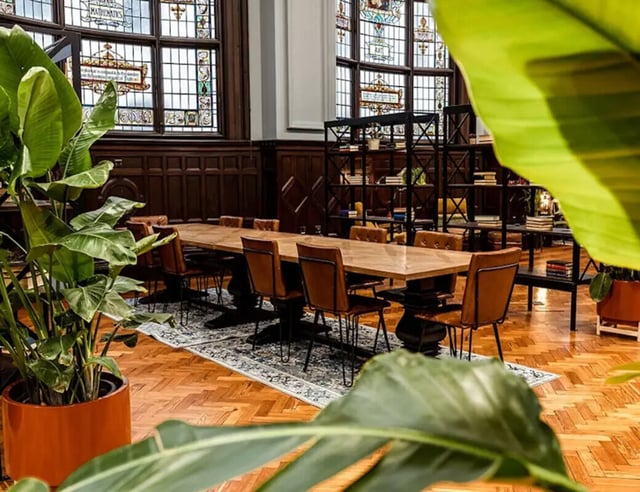 Large dining table leather chairs bookshelves plants communal area at John Bell House in Belfast Student Accommodation