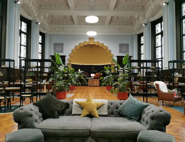 Plush sofa with plants and bookshelves common area at John Bell House in Belfast Student Accommodation