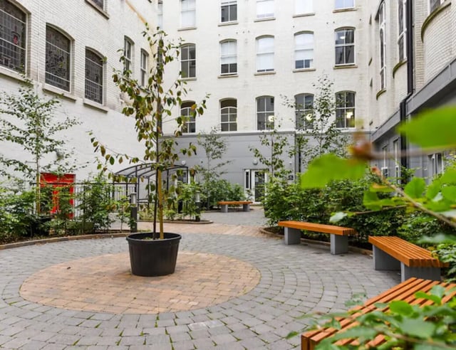 Courtyard with trees benches and building exterior at John Bell House in Belfast Student Accommodation