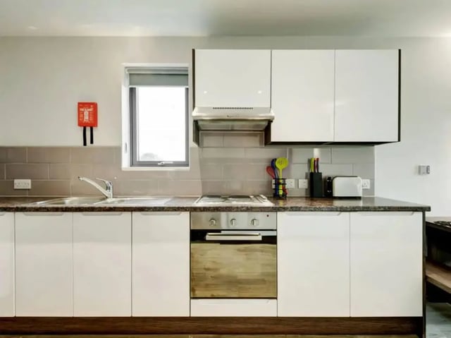 Modern kitchen with white cabinets stove sink and toaster kitchen at Cricket Field Court in Exeter Student Accommodation
