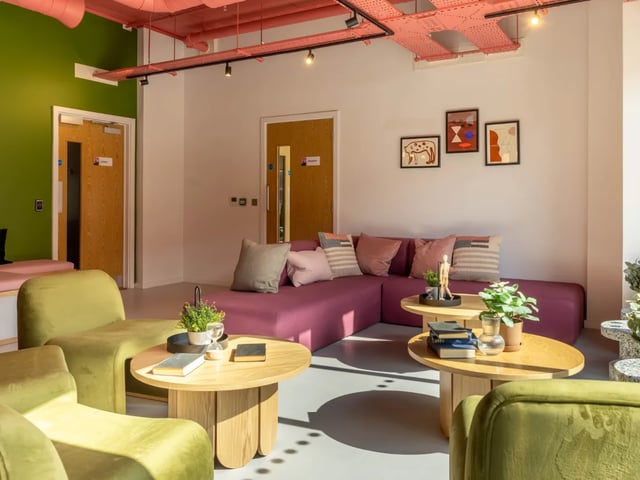 Modern lounge with plum sofa and green chairs living room at The Brook in Bath Student Accommodation
