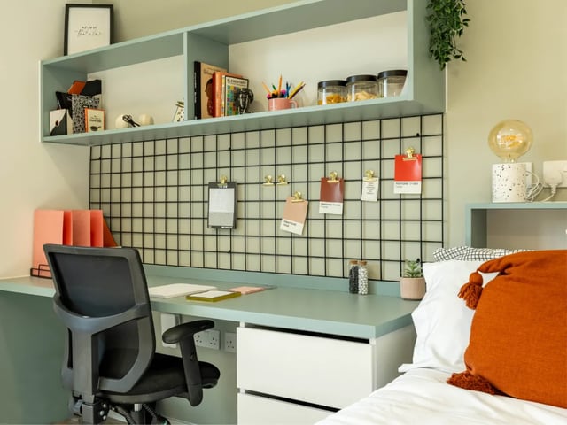 Desk chair shelves with books and bedside table study area at The Brook in Bath Student Accommodation