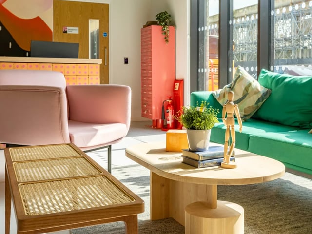 Pink armchair green sofa wooden table living room at The Brook in Bath Student Accommodation