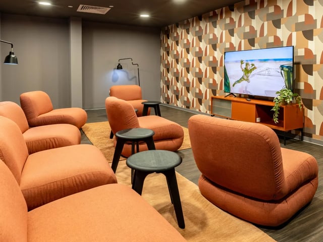 Orange modular sofas and TV screen living room at The Brook in Bath Student Accommodation