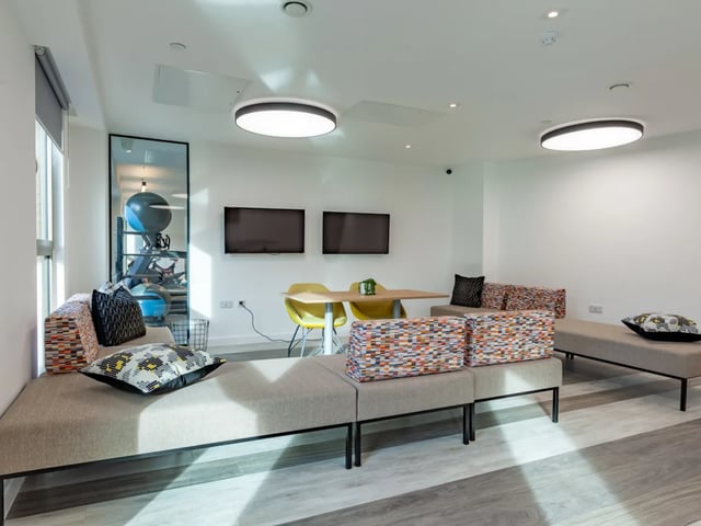 Modern lounge with sofas dining table and TVs living room at Pavilion Point in Brighton Student Accommodation