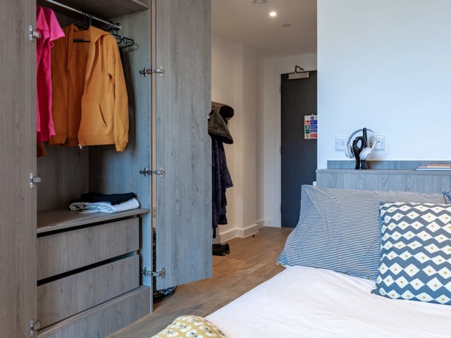 Wardrobe with clothes and bed with pillows bedroom at Pavilion Point in Brighton Student Accommodation