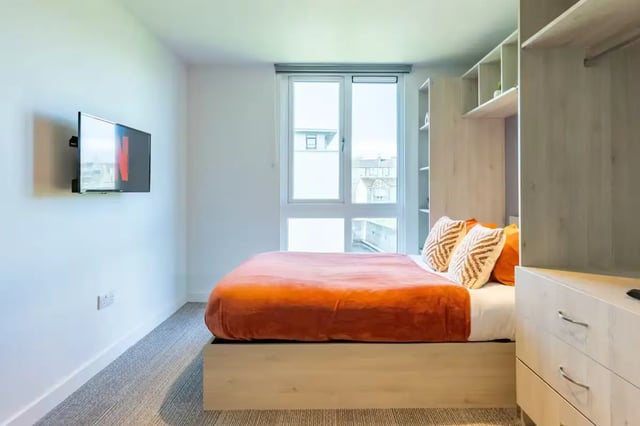 Bed with orange throw TV and wardrobe bedroom at Abeleven in Aberdeen Student Accommodation