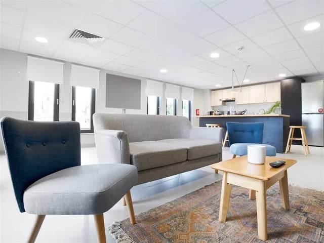 Sofa chairs table rug kitchen living area at Dun Holm House in Glasgow Student Accommodation