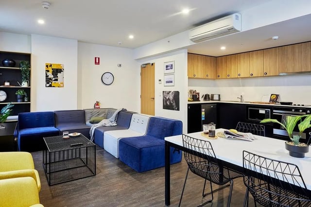 Modular sofa black coffee table modern kitchen living area at Scape Queensberry in Melbourne Student Accommodation