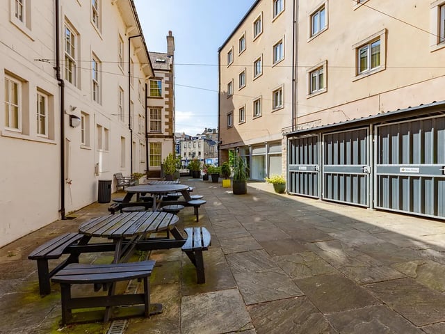 Wooden picnic tables on paved courtyard exterior at Cable Street Lancaster in Lancaster Student Accommodation