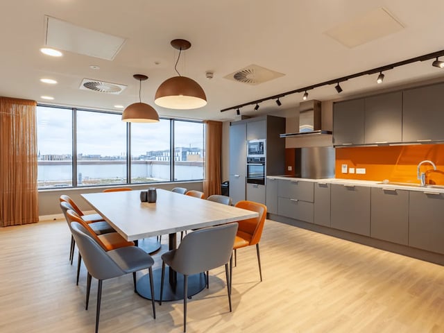 Dining table chairs kitchen counter and cabinets communal kitchen at Benson Yard in Liverpool Student Accommodation