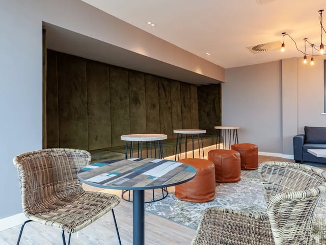 Wicker chairs round tables brown ottomans communal area at Benson Yard in Liverpool Student Accommodation