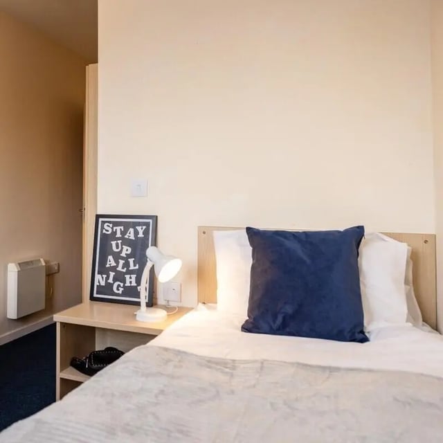 Bed with blue pillow framed art and lamp bedroom at Okeford House in Bournemouth Student Accommodation